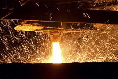 thin stream of molten steel pouring out, sparks flying